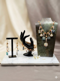 Handmade peach coral bead and charm earring and necklace set displayed on marble
