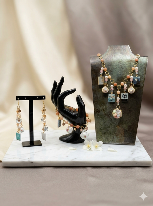 Handmade peach coral bead and charm earring and necklace set displayed on marble